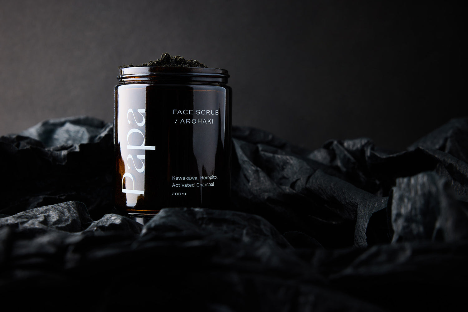 A recyclable jar of Arohaki Face Scrub made by Papa Skincare with black sand from Arohaki Bay